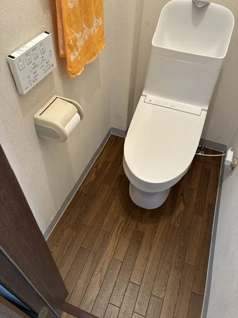 交換後の便器と壁のリモコン・クッションフロアを貼り替えた床(施工後)|トイレ便器交換・床貼り替え